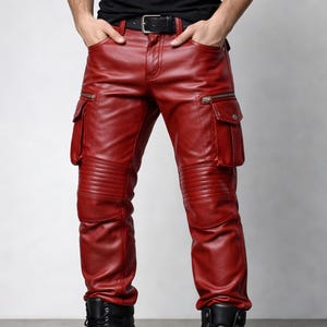 Puede incluir: Pantalones cargo de cuero rojo con múltiples bolsillos y detalles con cremallera. Los pantalones tienen paneles acanalados en las rodillas y un cinturón negro. Los pantalones se usan con botas negras.