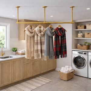 Pu&ograve; includere: Un appendiabiti in metallo dorato montato a soffitto che sostiene quattro sciarpe su grucce di legno. Le sciarpe includono un modello color crema a trecce, uno a quadri beige, uno in maglia grigia tinta unita e uno a quadri rossi, verdi e neri.