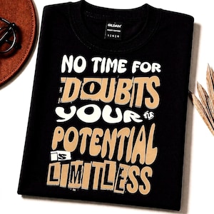 Op de afbeelding: Zwart T-shirt met de tekst "NO TIME FOR DOUBTS YOUR POTENTIAL LIMITLESS" in witte en bruine letters. Het shirt heeft een ronde hals en een Gildan-label. Het shirt ligt op een witte ondergrond.
