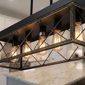 May include: A rectangular, black and gold-toned metal light fixture with five Edison-style light bulbs. The fixture has a geometric cage design and is suspended from the ceiling. The bulbs are lit, casting a warm glow.