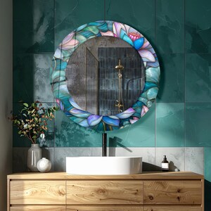 May include: A round wall mirror featuring a decorative frame with a colorful stained glass pattern of overlapping lotus petals in shades of teal, blue, purple, and white. The reflective surface shows a shower fixture and dark tiled walls.