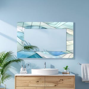 May include: Rectangular wall mirror with a decorative border featuring a wave-like pattern in shades of blue and white. The mirror is mounted on a light blue wall above a wooden vanity with a white sink.