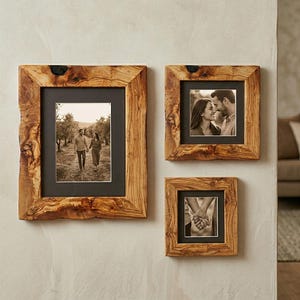 May include: A set of three wooden picture frames with natural, rustic edges. Each frame holds a black and white photograph. The frames are different sizes and are mounted on a neutral-colored wall, creating a gallery wall effect.