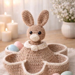 May include: A handmade crochet bunny basket in tan with a white collar, holding pastel-colored eggs. The basket has a unique flower-like shape with multiple compartments. The text "PDF Pattern English" is at the top.