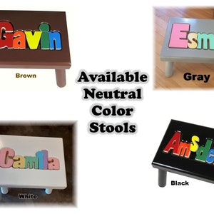 May include: Four small wooden stools in brown, gray, white, and black. Each stool has a name spelled out in colorful, raised letters. The text "Available Neutral Color Stools" is in the center of the image.