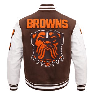 May include: Brown and white varsity jacket with the word "BROWNS" in orange block letters across the back. The jacket features a bulldog logo in orange and white. The sleeves are white, and the jacket has a striped collar and cuffs.