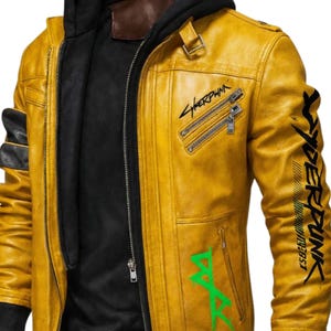 May include: Mustard yellow leather jacket with a black interior and a black hooded sweatshirt underneath. The jacket features the word "Cyberpunk" in black and green lettering, along with other graphics and zippers.