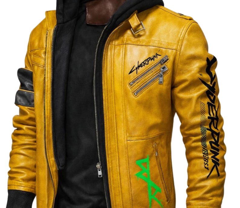 May include: Mustard yellow leather jacket with a black interior and a black hooded sweatshirt underneath. The jacket features the word "Cyberpunk" in black and green lettering, along with other graphics and zippers.