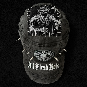 May include: Black denim cap with a distressed finish, featuring a patch with a grim reaper design and the text "All Flesh Rots." The cap is adorned with silver spikes along the brim, creating a gothic aesthetic.
