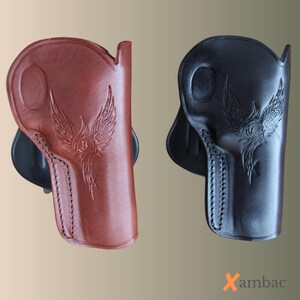 May include: Two leather gun holsters, one in brown and one in black, each with an embossed phoenix design. The holsters are stitched and have a belt loop. The brand name "Xambac" is visible in the bottom right corner.