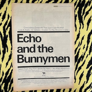 May include: Black and white newspaper clipping with a headline that reads "Echo and the Bunnymen". The article is about the band's new single, "Crocodiles Zimbo", and their upcoming tour dates.