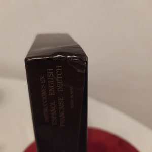 Puede incluir: Primer plano del lateral de una caja marr&oacute;n con el texto "Instrucciones en: Espanol - English Francaise - Deutsch" y "Made in Spain" impreso en ella.