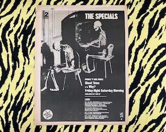 May include: Black and white poster for The Specials, featuring skeleton figures. The poster includes the band's name, song titles "Ghost Town" and "Why?", and concert dates. The background is a yellow and black zebra print.
