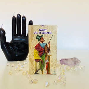 Op de afbeelding: Tarot kaartspel doos met een kleurrijke illustratie van een man in een paarse hoed en een rood-gouden gewaad die een stok vasthoudt. De doos is gelabeld "Tarot del III Milenio".