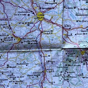 May include: A detailed map of the Rhône-Alpes region in France, showing cities such as Lyon, Grenoble, and Valence. The map uses a colour-coded system for roads and elevations, with place names in black.