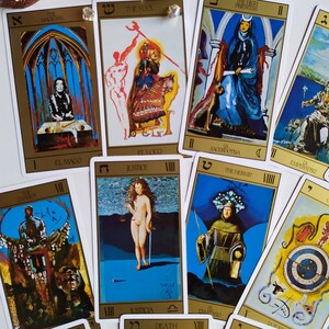Puede incluir: Una baraja de tarot con bordes dorados e ilustraciones coloridas. Las cartas presentan im&aacute;genes del Mago, el Loco, la Sacerdotisa, la Emperatriz, la Justicia, el Ermita&ntilde;o, la Muerte y el Mundo.