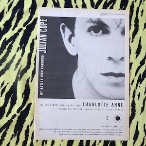 Può includere: Poster in bianco e nero con Julian Cope, con il testo "MY NATION UNDERGROUND" e "CHARLOTTE ANNE". Il poster è su uno sfondo di tessuto a righe zebrate giallo e nero. Il poster pubblicizza un nuovo album.