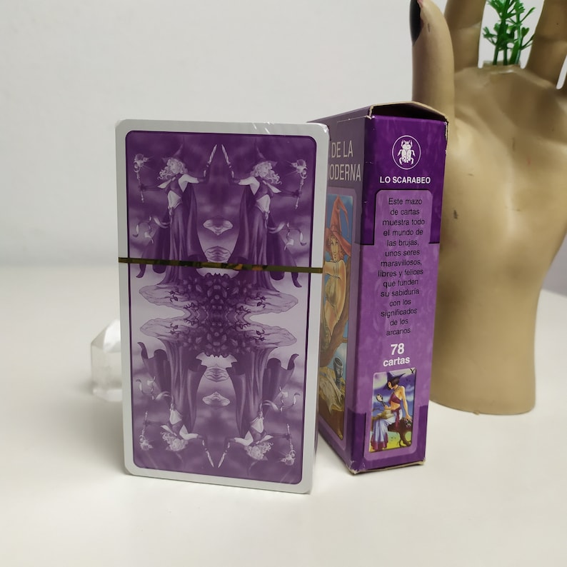 May include: A purple tarot deck box with a gold border and the text "DE LA ODERNA LO SCARABEO" on the front. The text below the title reads "Este mazo de cartas muestra todo el mundo de las brujas, unos seres maravillosos, libres y felices que funden su sabiduria con los significadne de los arcanos 78 cartas".