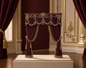 May include: A miniature stage archway featuring deep burgundy velvet curtains with intricate gold trim and tassels. The structure includes a dark wood-toned top valance with ornate gold carvings, standing on a rectangular off-white display base.