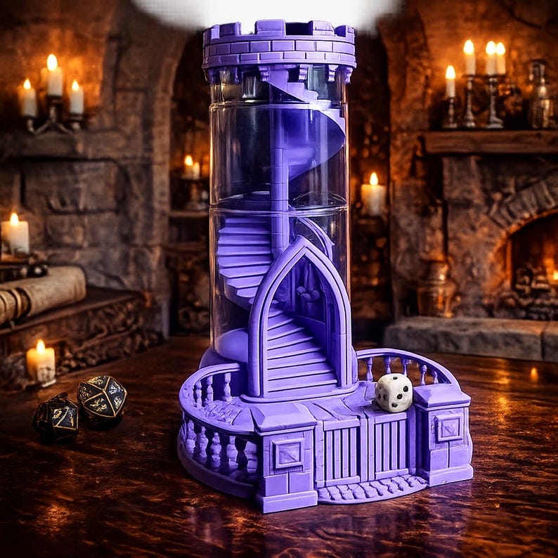 May include: A purple dice tower featuring a clear cylindrical center with an internal spiral staircase, a crenelated top, and a gated base with a balcony. A white six-sided die sits on the balcony, while two black dice rest nearby on the surface.
