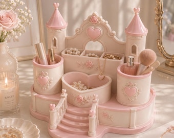 Può includere: Un organizzatore di gioielli decorativo rosa e bianco a due toni a forma di castello. Presenta dettagli a cuore e rosa, con scomparti per gioielli e pennelli per il trucco. L'organizzatore ha due torrette e un bacino a forma di cuore.