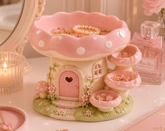 Può includere: Un portagioie a forma di fungo rosa, stravagante, con pois bianchi. Il portagioie presenta una porta a forma di cuore, più livelli ed è decorato con fiori. Anelli e una collana di perle sono esposti.