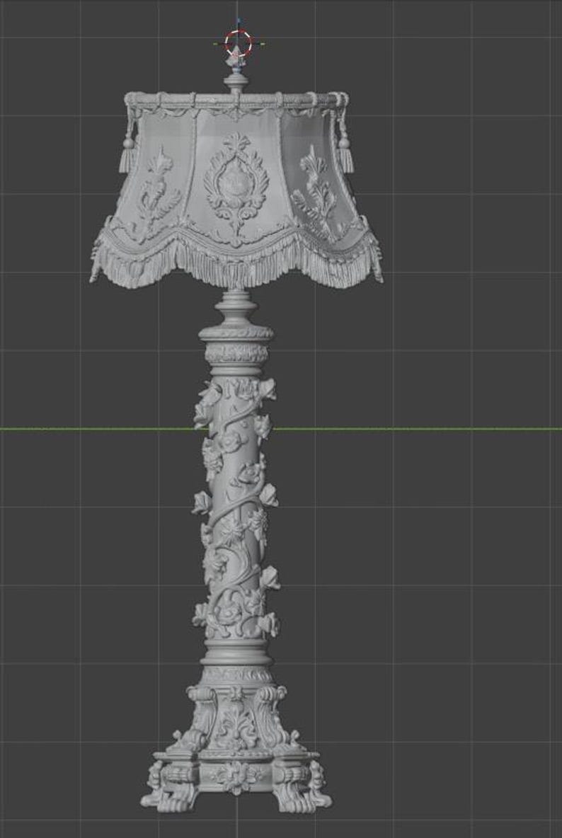 May include: A grey 3D digital model of a floor lamp featuring an ornate lampshade with fringe trim and a central column decorated with sculpted floral vines. The base is wide and detailed with intricate carvings, set against a dark grid background.