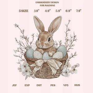 Op de afbeelding: Een borduurontwerp voor machine met een bruin konijn in een gevlochten mand met gespikkelde blauwe eieren. De mand heeft een crèmekleurige strik. Het ontwerp bevat de tekst "EMBROIDERY DESIGN FOR MACHINE" en maten van 9.9 cm tot 20.1 cm.