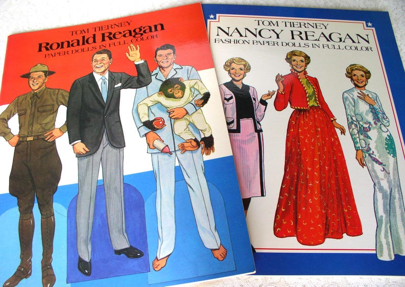 May include: Two paper doll books by Tom Tierney. The left book features Ronald Reagan in various outfits, including a suit and pajamas with a chimpanzee. The right book features Nancy Reagan in formal attire, including a red skirt and a white gown.