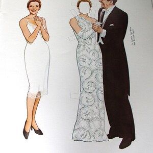 May include: A paper doll set featuring a figure in a white slip dress and a figure in a white beaded lace gown with a fern design, paired with a figure in a black tuxedo. Text reads: Inaugural-ball gown of white satin, overlaid with elaborately beaded lace in a fern design. Do Not Cut Out White Area Between Figures.