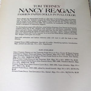 May include: A paperbound book titled Tom Tierney Nancy Reagan Fashion Paper Dolls in Full Color. The cover features black text on a cream background, detailing the collection of one doll and 31 outfits, measuring 9.25 inches by 12.25 inches.