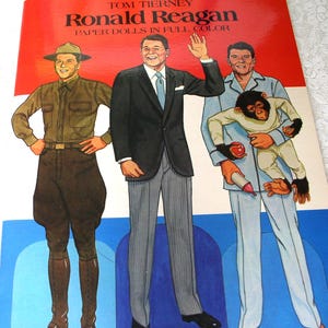 May include: A Tom Tierney Ronald Reagan Paper Dolls in Full Color book cover featuring three illustrations of Ronald Reagan in different outfits: a brown military uniform, a black suit with grey trousers, and light blue pajamas holding a chimpanzee.
