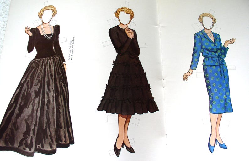 May include: Three paper dolls with blonde hair and blank faces. The first wears a black long-sleeved gown with a full skirt and pearl necklace. The second wears a black dress with a tiered ruffled skirt. The third wears a blue suit with green patterns.