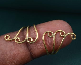 Puede incluir: Dos pendientes tipo ear cuff de metal dorado con un delicado diseño de alambre en espiral. Cada pieza consta de tres bucles curvos interconectados que terminan en pequeños extremos redondeados, creando una estructura fluida y abierta.