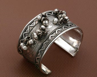 Puede incluir: Un brazalete de plata con detalles intrincados. La pulsera presenta una serie de adornos redondeados en relieve y patrones detallados. Los bordes están adornados con un diseño ondulado. El diseño abierto facilita su uso.