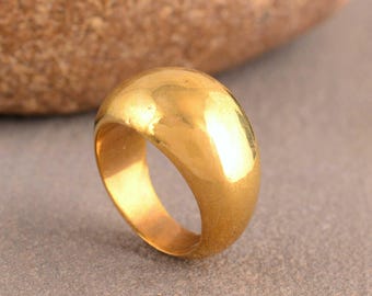 Puede incluir: Un anillo dorado con un diseño liso y redondeado. El anillo tiene un acabado pulido, que refleja la luz. Es una joya sencilla y elegante.
