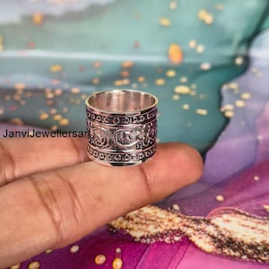 Op de afbeelding: Een zilveren ring met ingewikkelde bloemen- en geometrische patronen. De ring is breed, met gedetailleerde ontwerpen rond de band. De tekst "JanviJewellersart" is zichtbaar op de achtergrond.