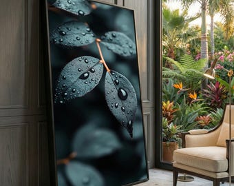 Puede incluir: Una impresión artística enmarcada que presenta un primer plano de hojas verdes oscuras con gotas de agua. Las hojas tienen una apariencia texturizada y están sobre un fondo oscuro y borroso. La obra de arte está apoyada contra una pared de madera, con una vista de un exuberante jardín visible a través de una ventana.