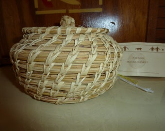 May include: A woven basket made of natural materials, with a label that reads "Papago Indian Basket".