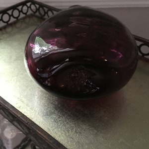 Op de afbeelding: Een ronde flesstopper van donkerpaars glas.