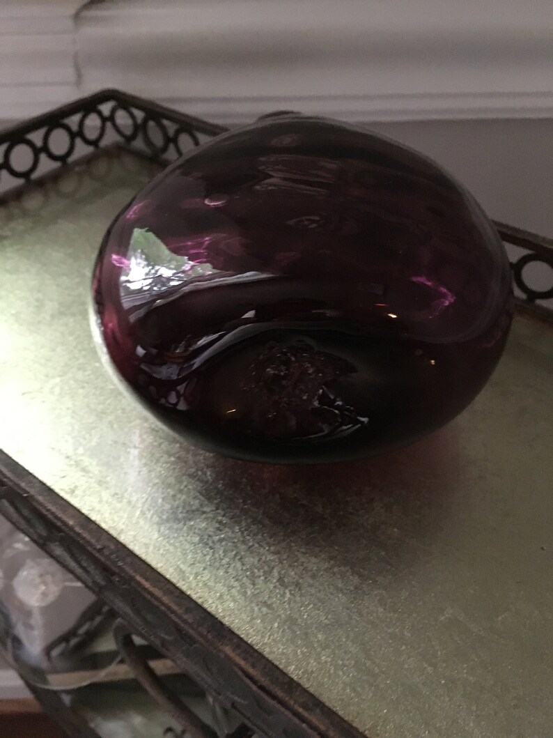 Op de afbeelding: Een ronde flesstopper van donkerpaars glas.