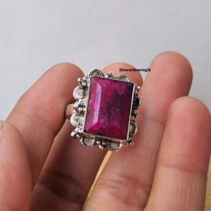 Pu&ograve; includere: Anello in argento con una grande gemma rettangolare rosa intenso. La gemma &egrave; incastonata in una cornice d'argento ornata con un bordo smerlato. Un gioiello di grande effetto.
