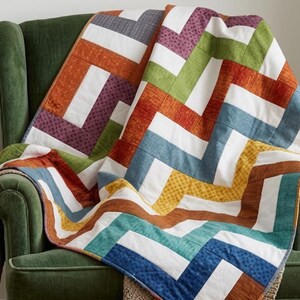 Puede incluir: Una colcha de patchwork con un patrón de espiga repetitivo construido con tiras de tela rectangulares en varios colores, incluyendo naranja, verde, morado, azul, amarillo y blanco, con sutiles patrones texturizados en las piezas de tela de color.
