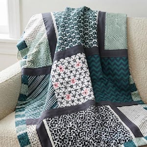 May include: A patchwork quilt featuring various fabric squares in shades of teal, dark green, white, and black. The patterns include chevrons, floral motifs, small pink flowers, geometric grids, and abstract shapes, all separated by solid dark gray sashing.