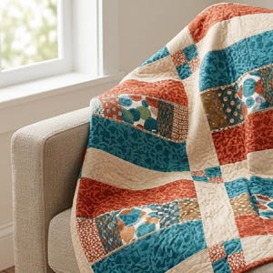 May include: A patchwork quilt featuring a repeating pattern of rectangular and square fabric blocks in shades of rust orange, teal blue, and cream. The quilt displays various printed textures, including floral, dotted, and abstract geometric motifs.