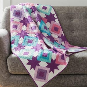 May include: A quilted blanket featuring a geometric pattern of nested squares and eight-pointed stars. The design incorporates a colour palette of purple, light purple, pink, and turquoise, all set against a white background with visible stitching.