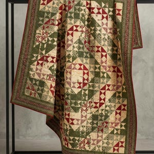 May include: A rectangular quilt featuring a patchwork design of cream, forest green, and deep red fabric squares. The pattern consists of intricate geometric shapes and floral motifs, finished with a decorative border in matching colors.