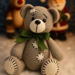 May include: A handmade gray crochet teddy bear with a green bow, white accents, and black stitching. The bear has a stitched patch design and is sitting in a snowy scene with a reindeer and Santa Claus in the background.
