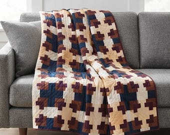 Könnte beinhalten: Eine Steppdecke mit einem geometrischen Muster aus ineinandergreifenden Formen in Marineblau, Dunkelbraun und Creme. Der Stoff zeigt ein sich wiederholendes Blockdesign mit sichtbaren diagonalen Steppnähten auf der gesamten Oberfläche.