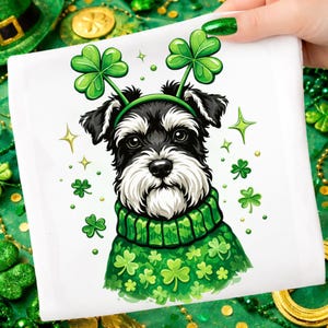 Puede incluir: Un cuadrado blanco con un Schnauzer de dibujos animados que lleva un suéter verde adornado con tréboles y una diadema de tréboles. El perro tiene pelaje blanco y negro y una barba blanca. Tréboles verdes y estrellas doradas están esparcidos alrededor del perro.